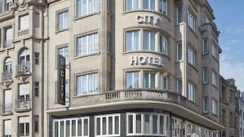 Un edificio histórico con un letrero que dice “CITY HOTEL”, que presenta un estilo arquitectónico clásico con múltiples ventanas y balcones.