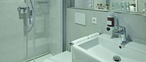 A modern bathroom with a glass-enclosed shower, a white sink, and a wooden vanity.