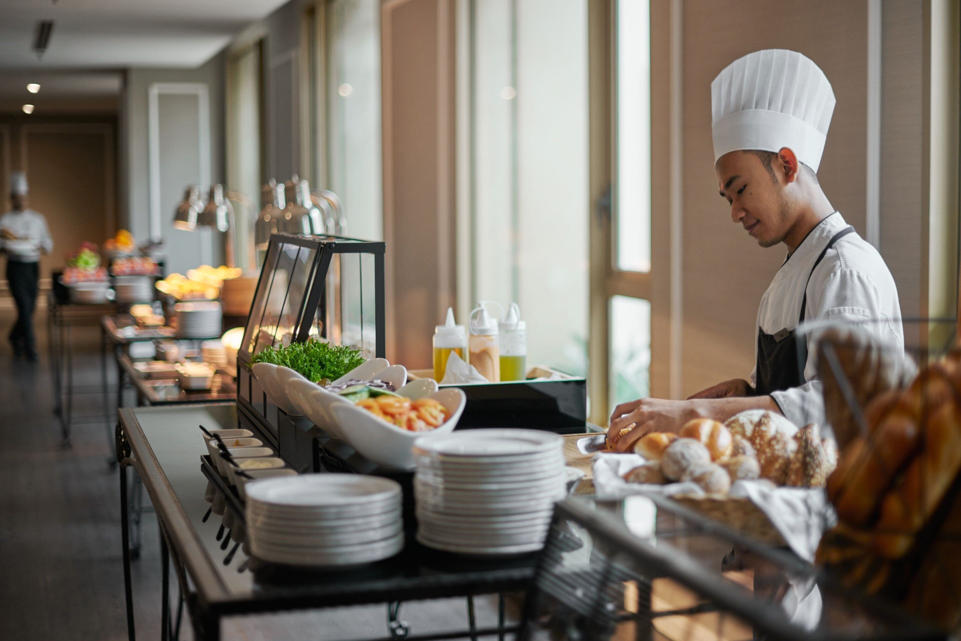 A buffet setup with various food items and a chef in uniform.