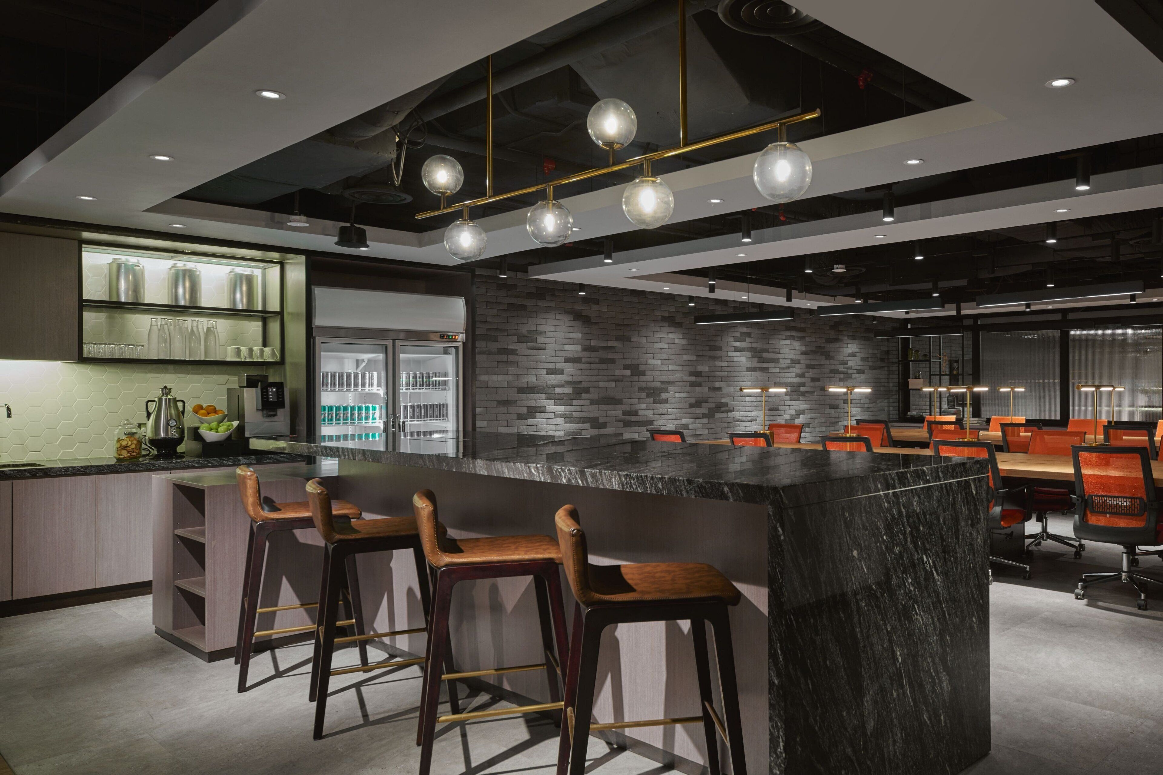 Un área de bar moderna con una barra de mármol, taburetes de madera y un fondo de pared de ladrillo.