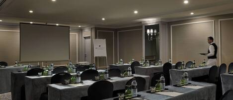 A conference room with tables set for a meeting, equipped with water bottles and nameplates.