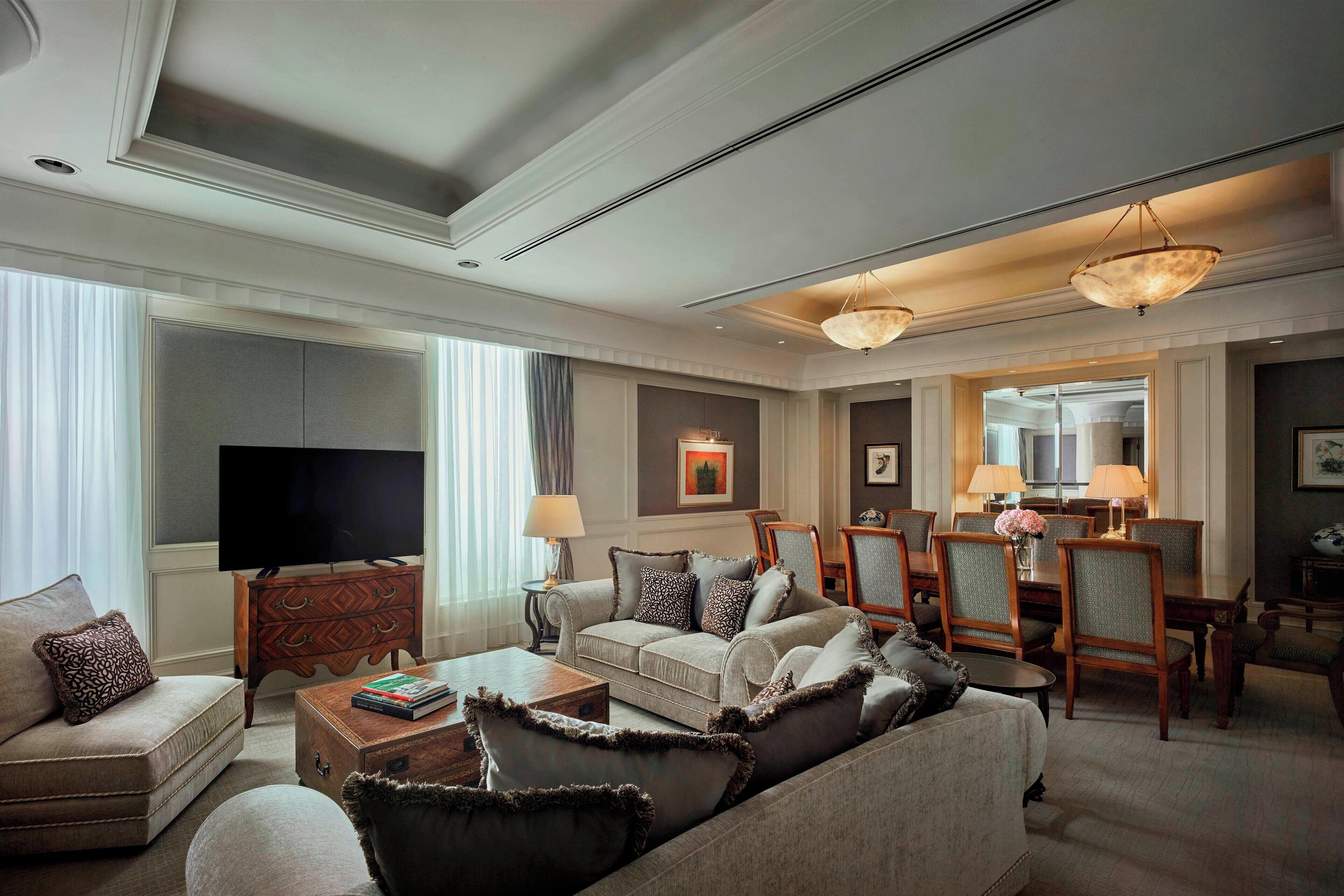 A spacious living room with a large flat-screen TV, comfortable seating, and a dining area with chairs and a table.