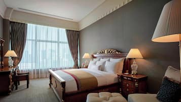 A hotel room with a large bed, two bedside tables with lamps, a chair, and a window with curtains.