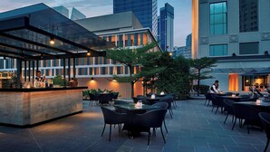 An outdoor dining area with tables and chairs, a bar counter, and a glass enclosure. - JW Marriott Kuala Lumpur (Kuala Lumpur)