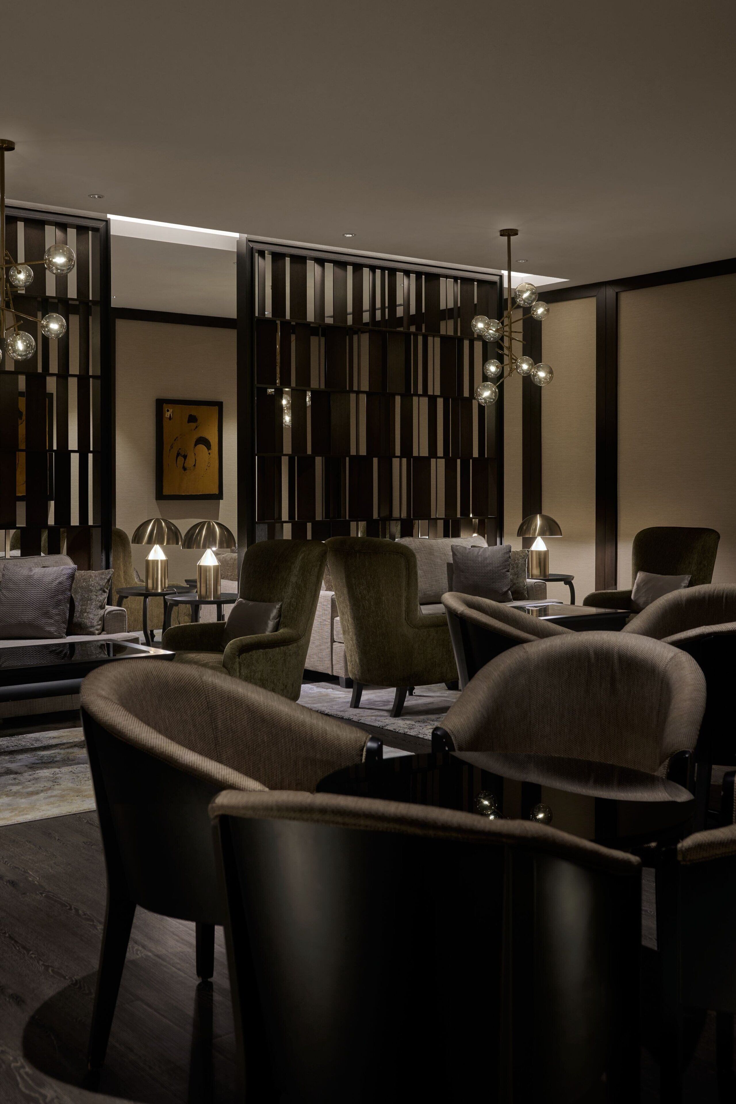 Una sala de estar moderna con un sofá modular, sillones y un panel decorativo en la pared.
