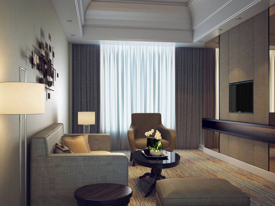 Una habitación de hotel moderna con sofá, sillón, mesa de centro y televisor de pantalla plana.