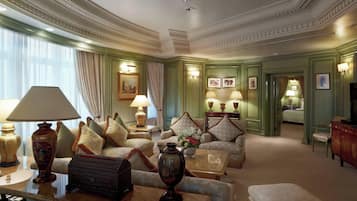 A spacious, elegantly furnished living room with a large sofa, armchairs, a coffee table, and a fireplace.