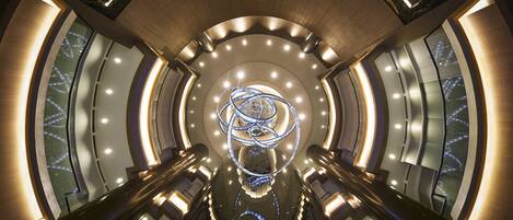 A modern interior with a central spiral staircase, illuminated by recessed lighting and a central light fixture.
