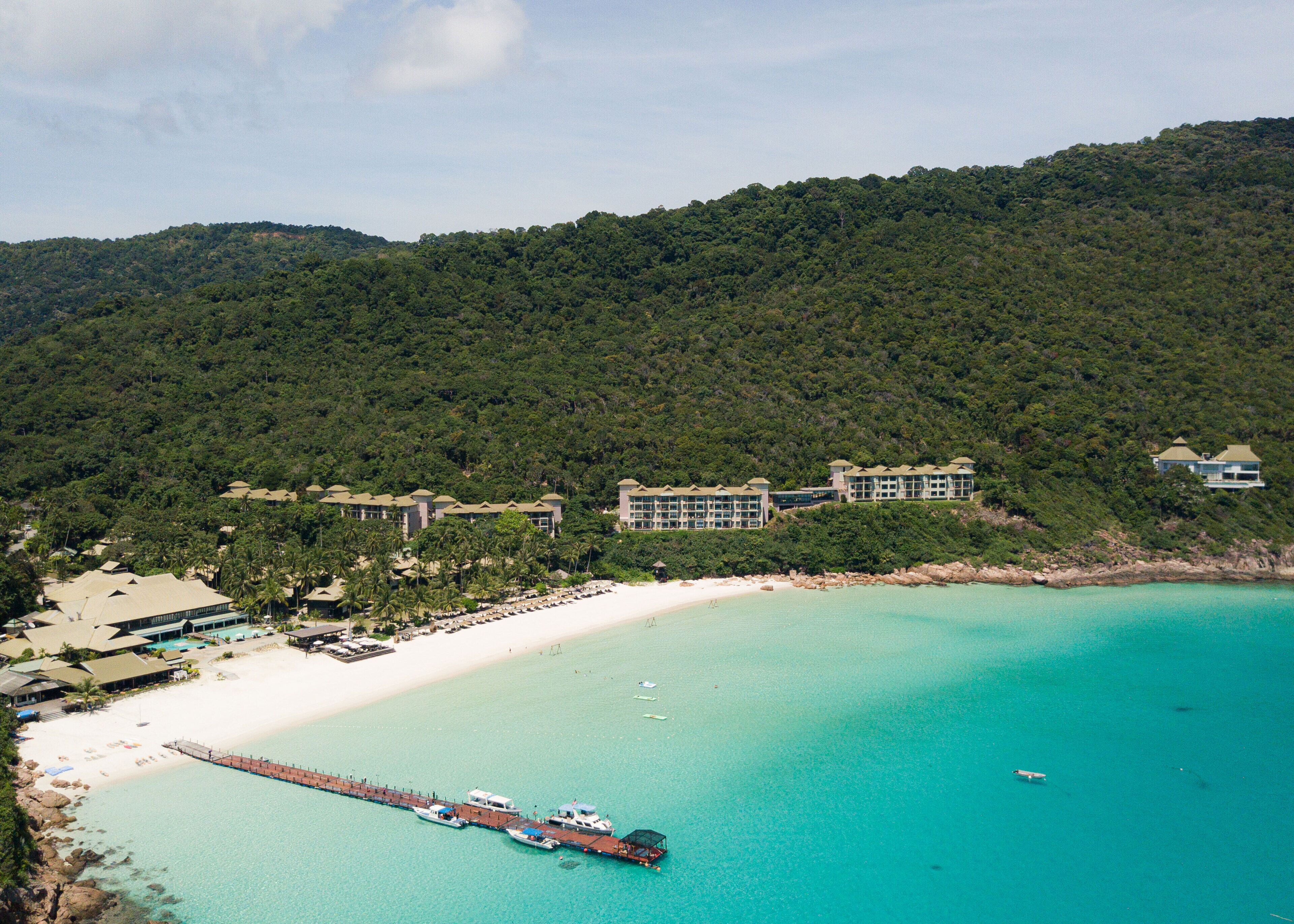 A resort with beachfront villas, a pier, and a beach.