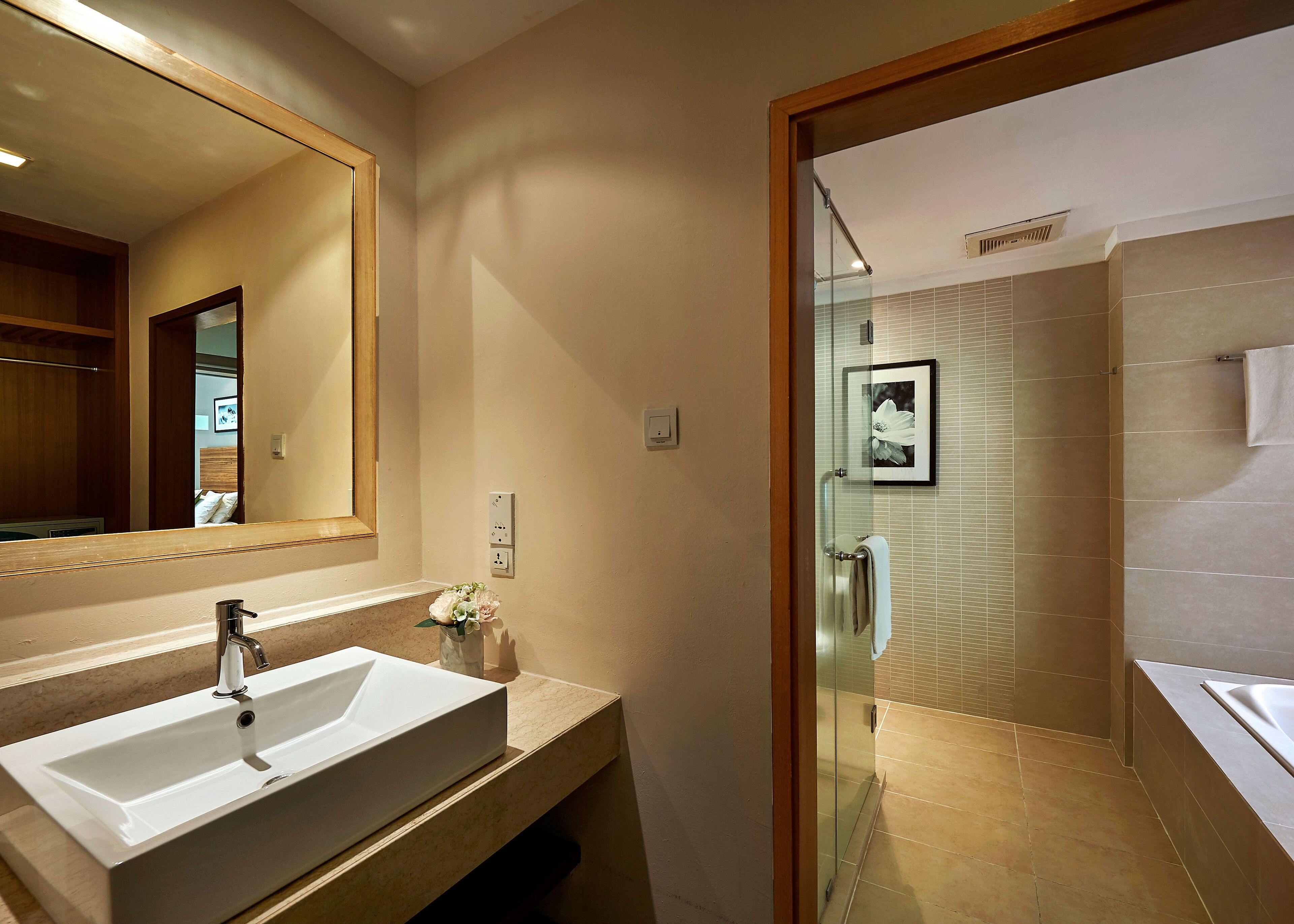 Un baño moderno con un espejo grande, un lavabo y una zona de ducha.