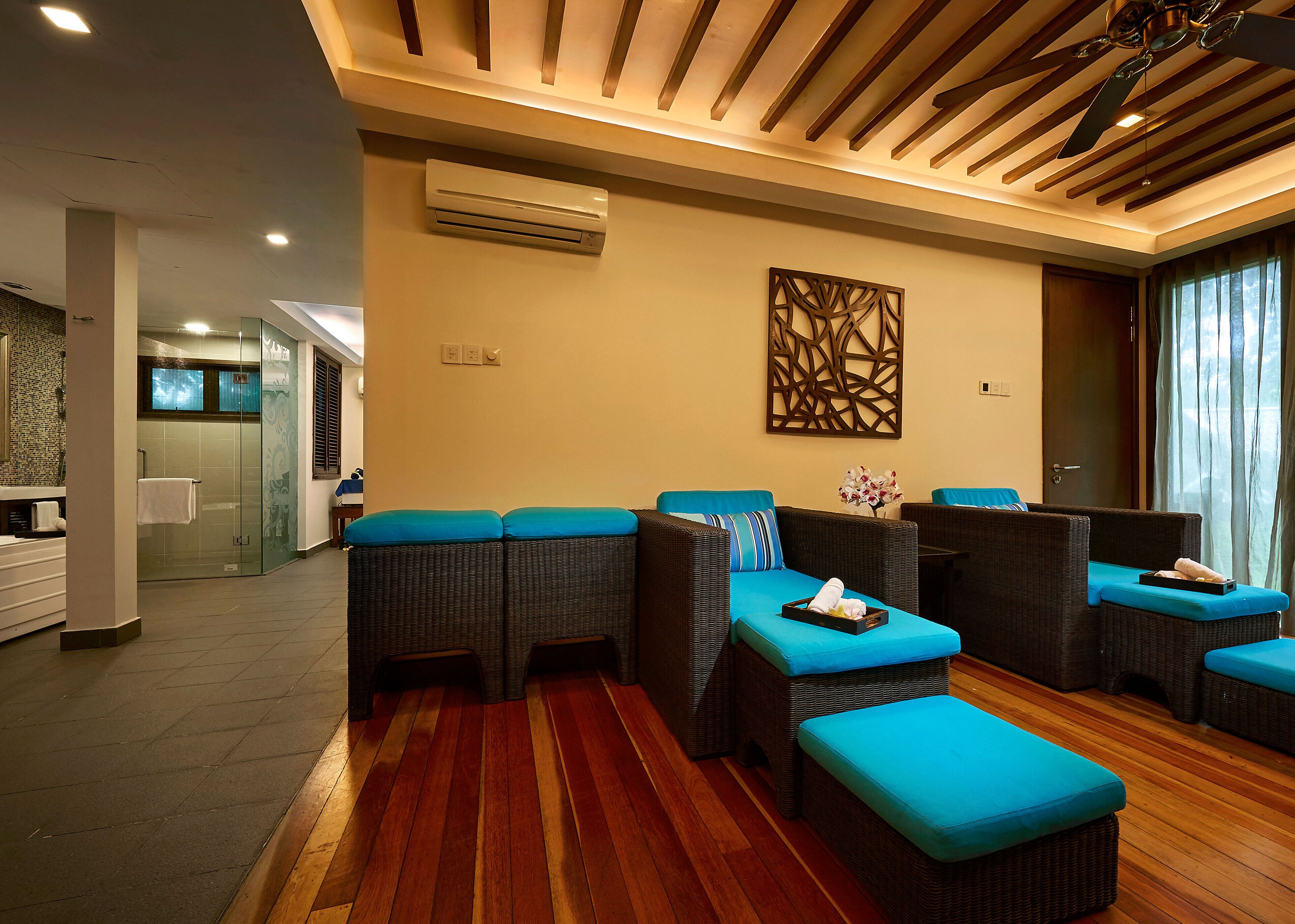 A hotel lobby with wicker furniture, a reception desk, and a glass shower enclosure.