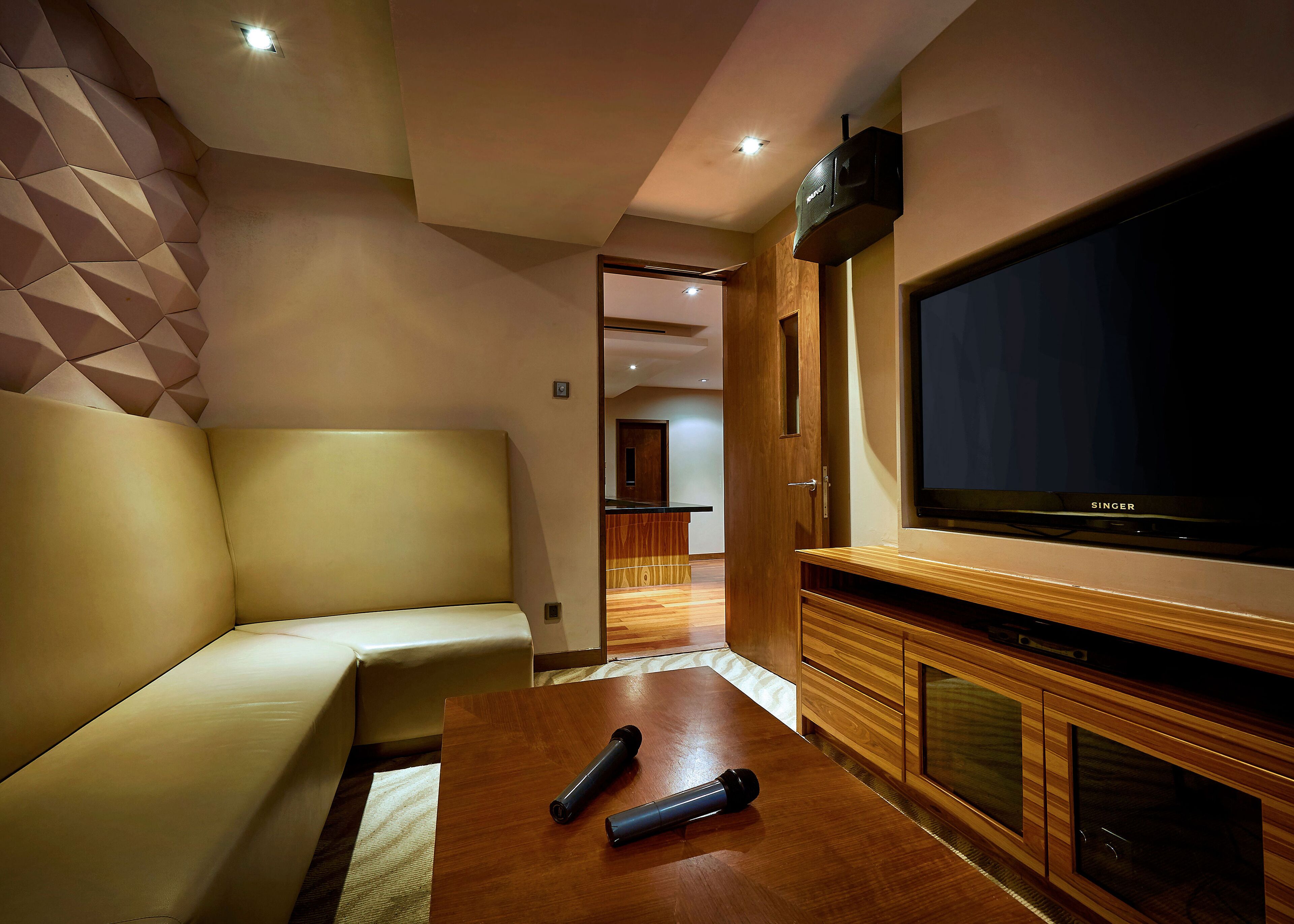 A modern living room with a sofa, a wooden coffee table, and a large flat-screen TV.
