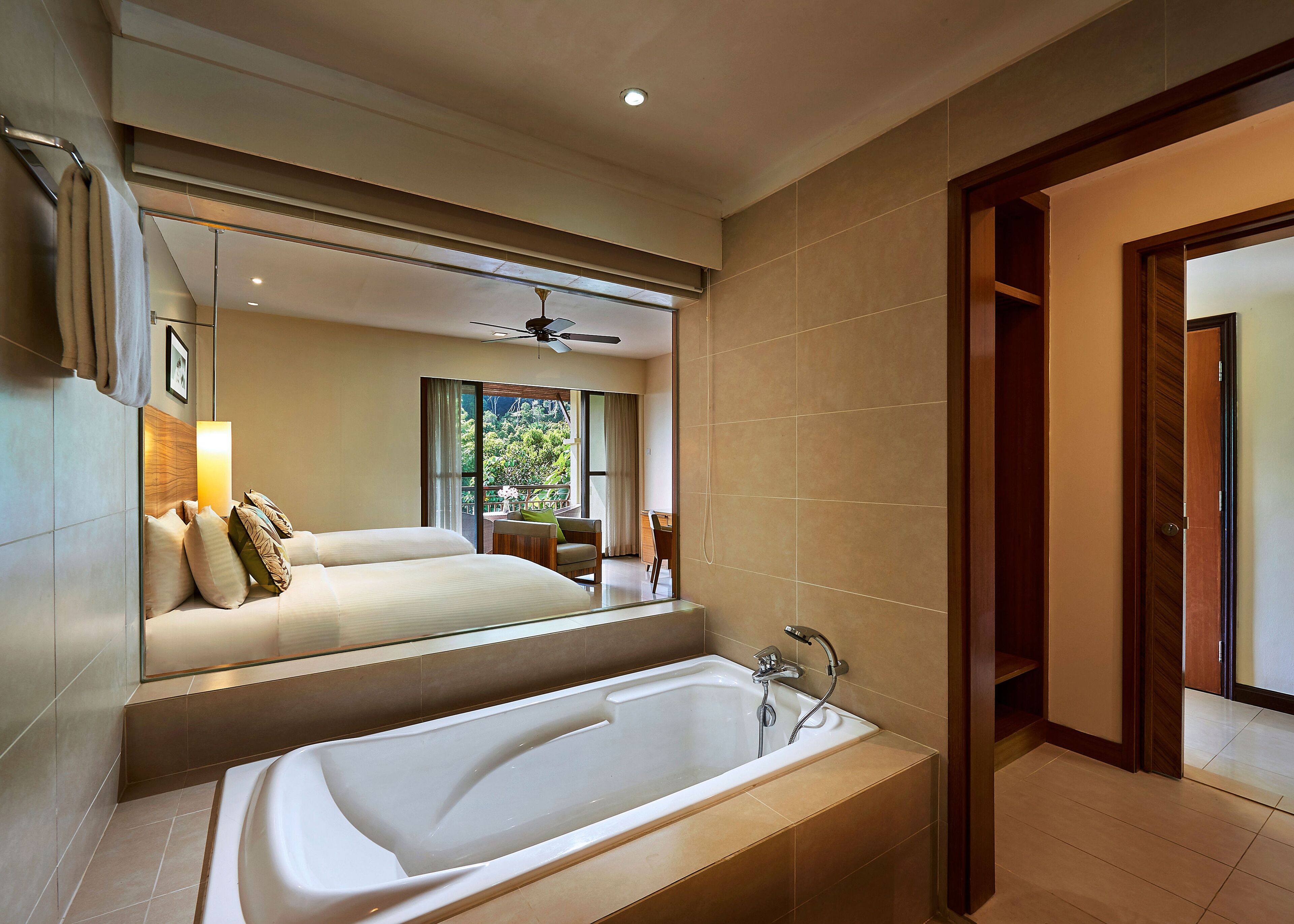 Habitación de hotel moderna con una cama grande, zona de estar con vistas y baño separado con bañera.