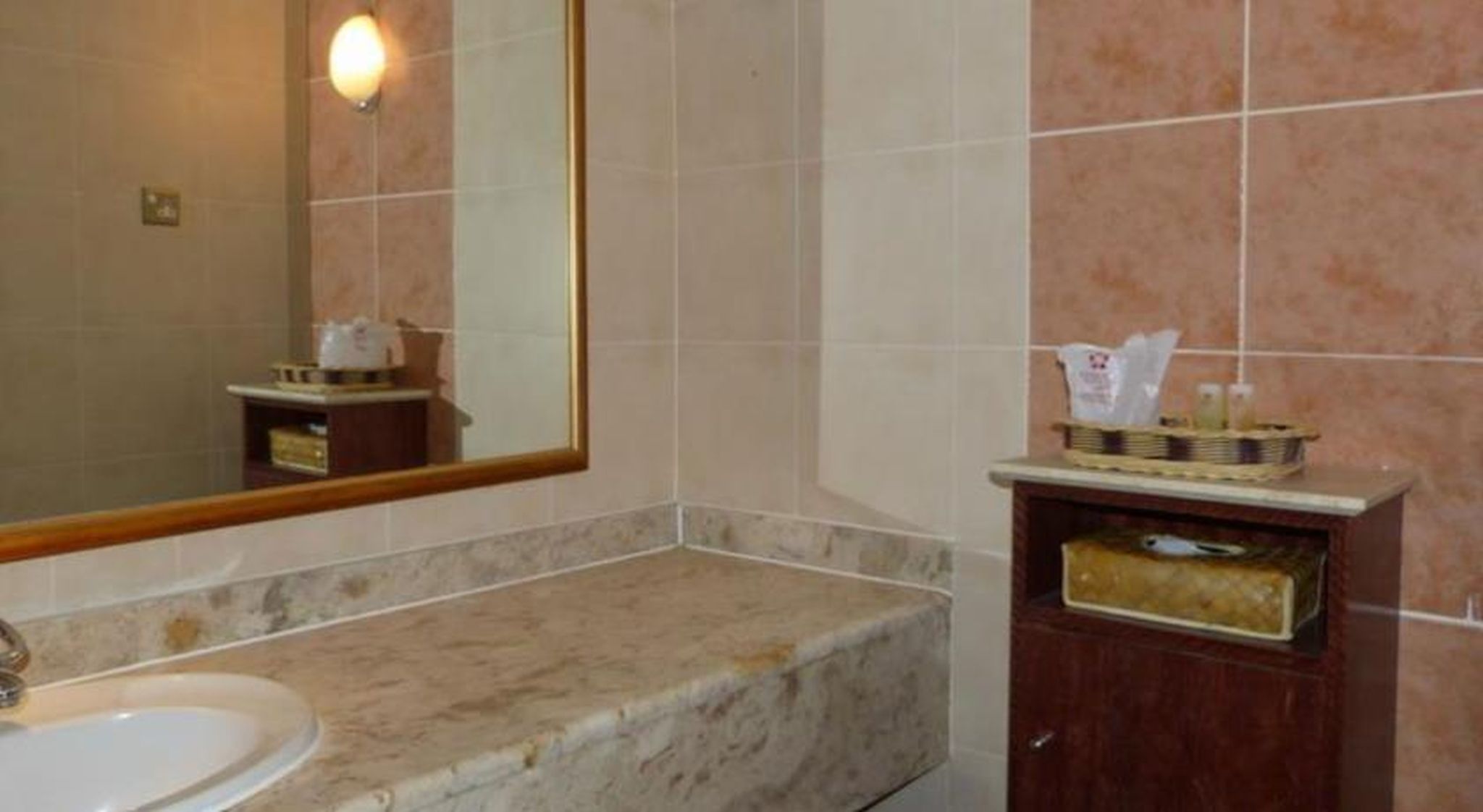 A bathroom with a sink, mirror, and toiletries.
