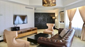Uma sala de estar moderna com televisão de tela plana, sofá de couro e um grande painel decorativo na parede.