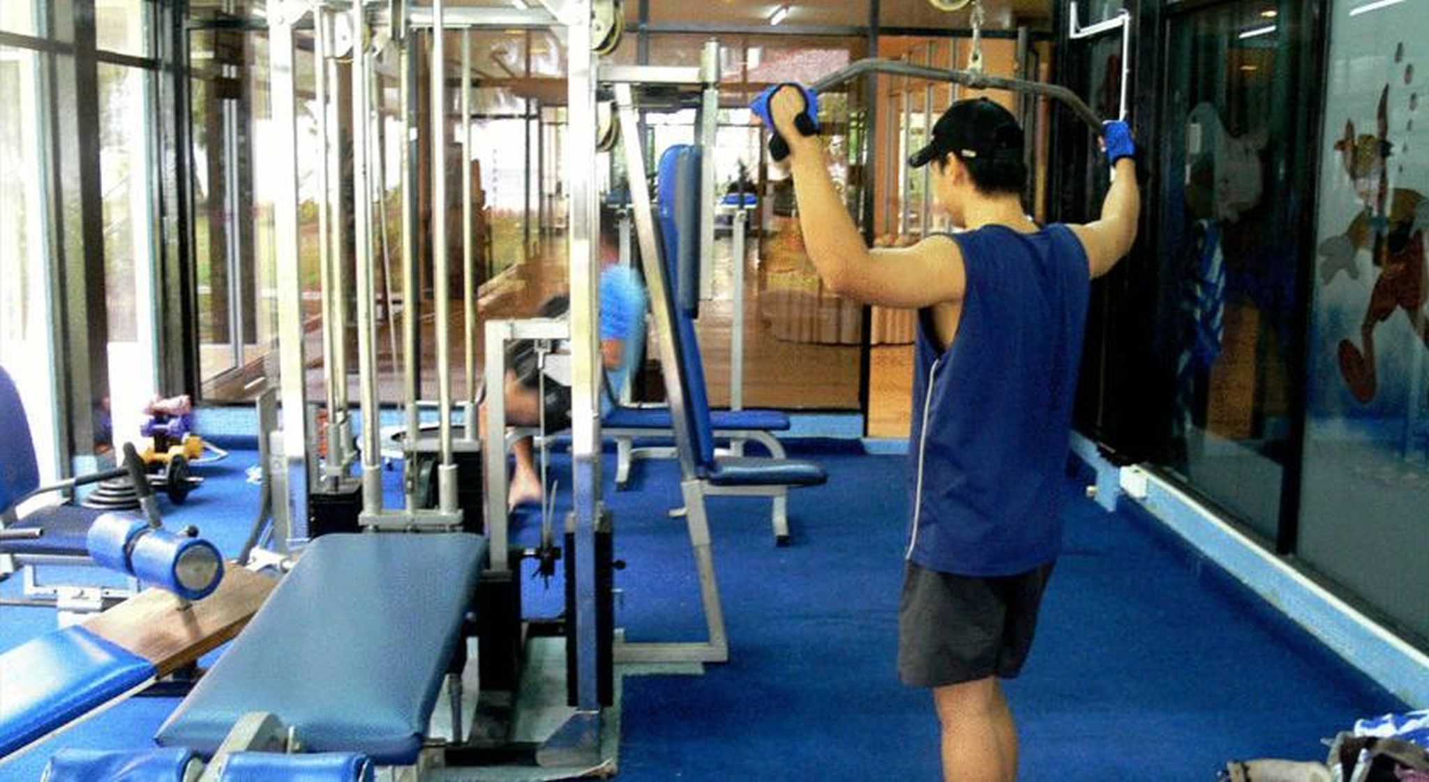 Ein Fitnessstudio mit Trainingsgeräten und einer Person, die an einer Klimmzugstange trainiert.
