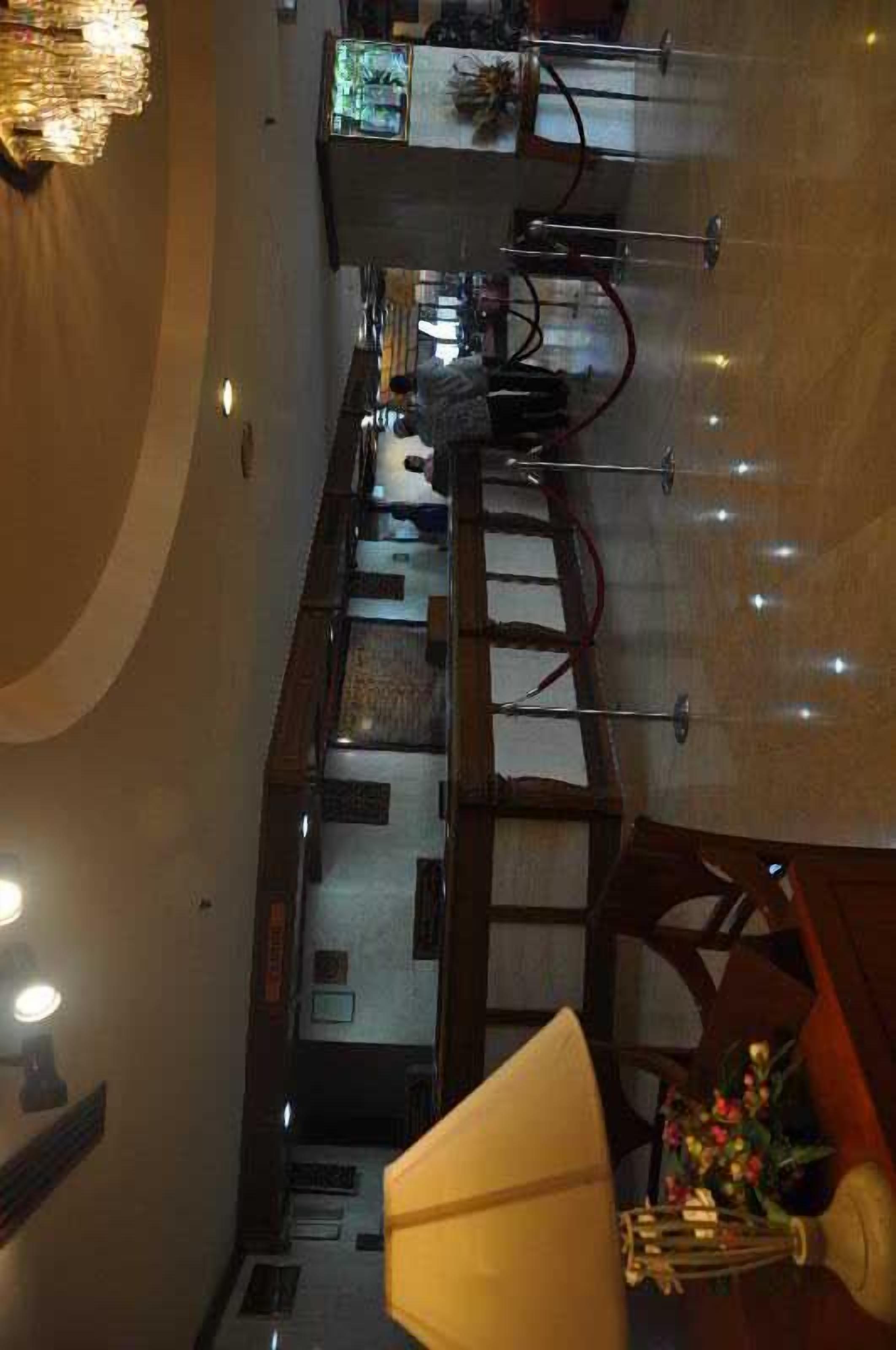A hotel lobby with a reception desk, a staircase, and a chandelier.
