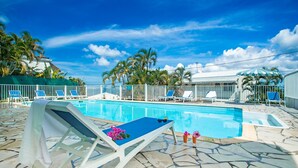 Una piscina al aire libre, sillones reclinables de piscina