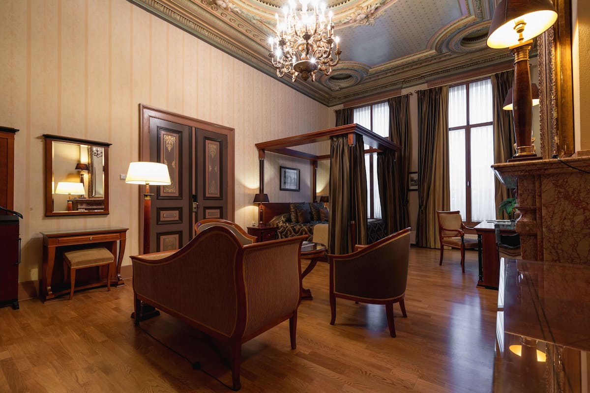 A spacious room with a large chandelier, wooden furniture, and a fireplace.