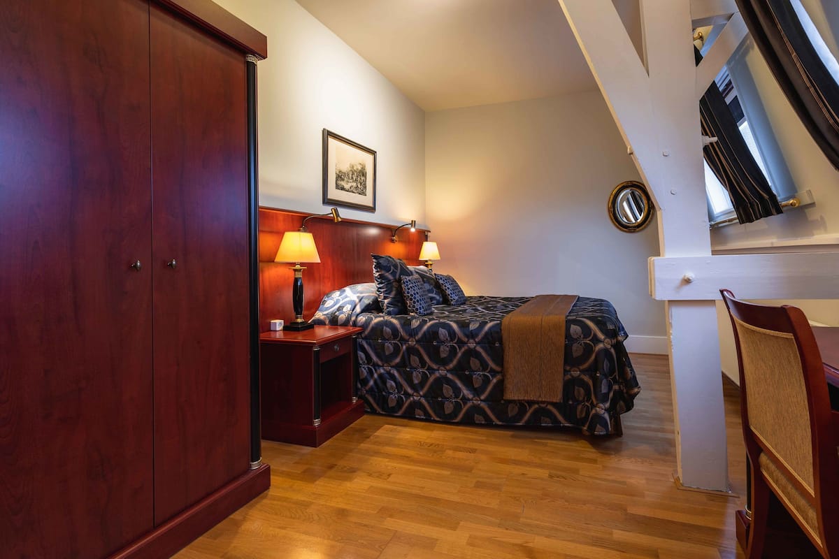 A bedroom with a bed, nightstands, a wardrobe, and a dining area with a chair.