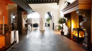A spacious corridor with a fireplace, a large mirror, and a potted plant.