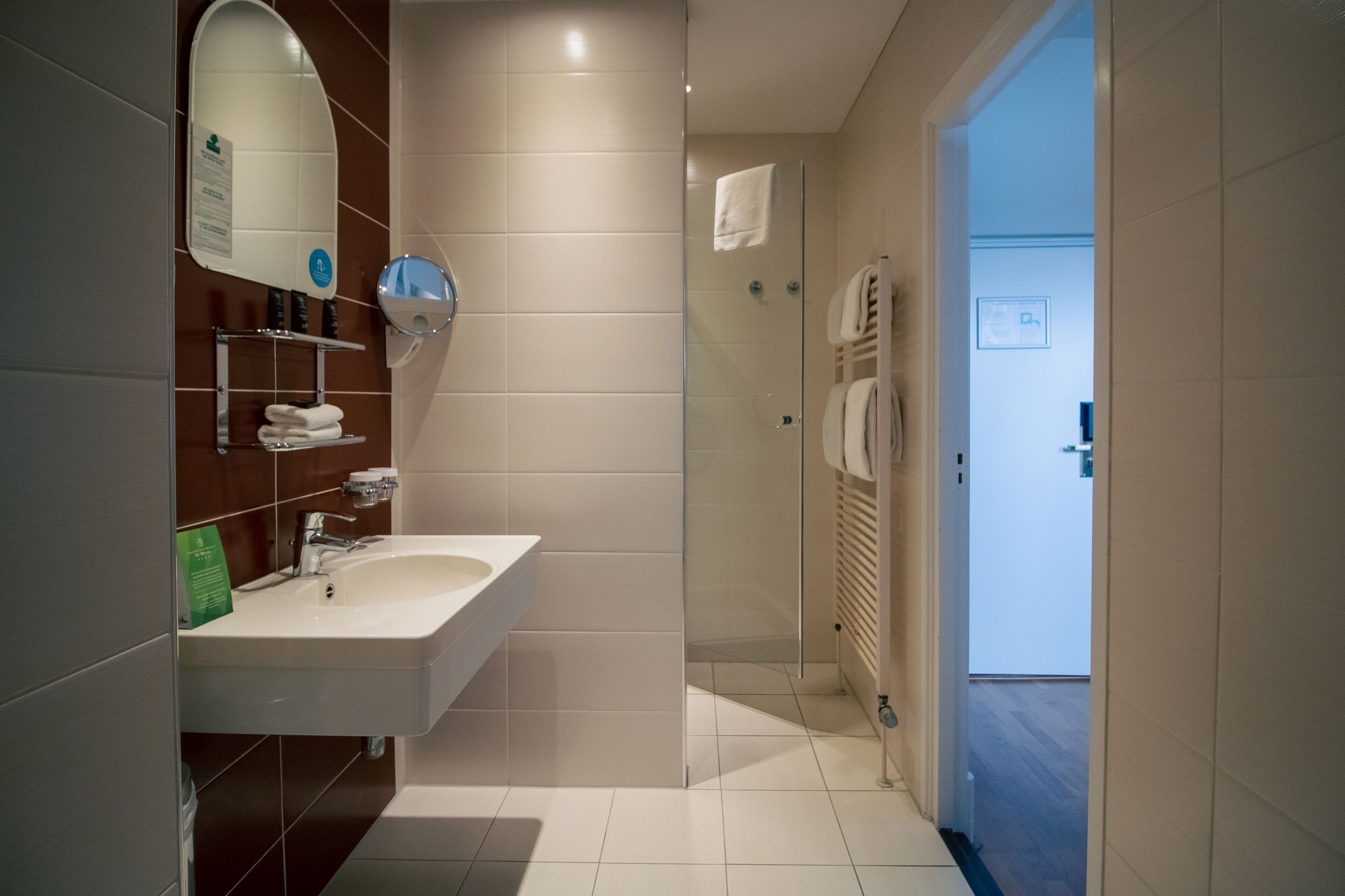 Ein modernes Badezimmer mit einem weißen Waschbecken, einem Spiegel und einer Duschkabine aus Glas.