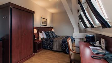 A bedroom with a bed, a desk, a wardrobe, and a window with curtains.