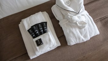 Un albornoz blanco ordenado y toallas sobre una cama marrón.