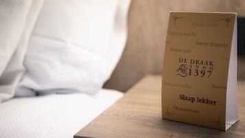 A bedside table with a book titled "DE DRAAK ANNO 1397" and a pillow.