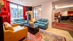 A modern hotel lobby with leather sofas, a coffee table, and a large red rug. - Bastion Hotel Maastricht Centrum (Maastricht)