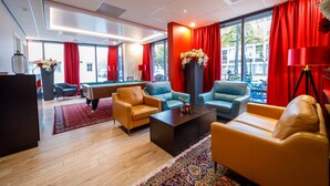 A modern hotel lobby with a pool table, comfortable seating, and large windows with red curtains. - Bastion Hotel Maastricht Centrum (Maastricht)