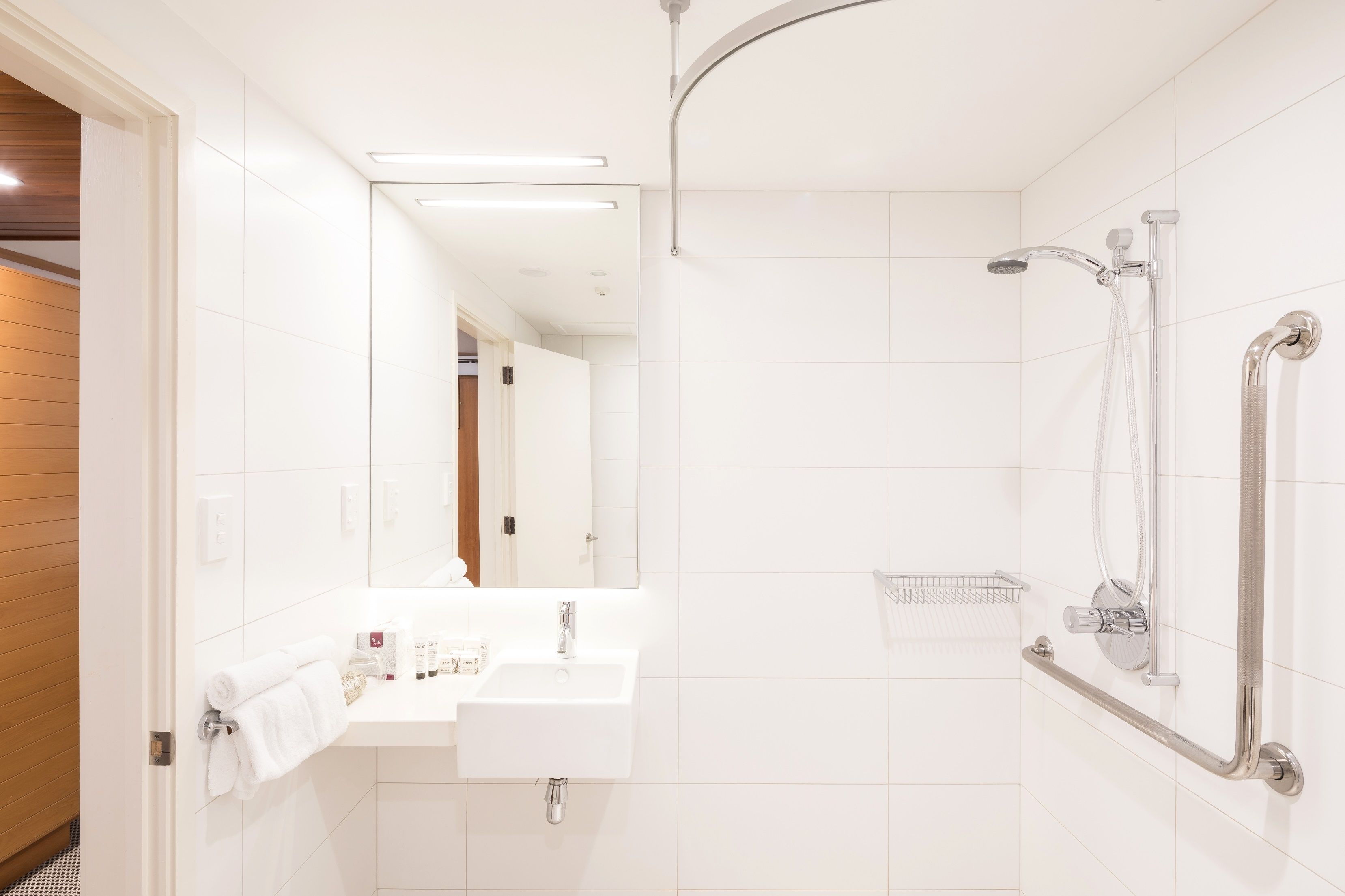 A modern bathroom with a white sink, mirror, and shower.