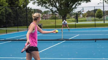 A tennis court with a net, a player in a pink top and black shorts, and another player in the background.