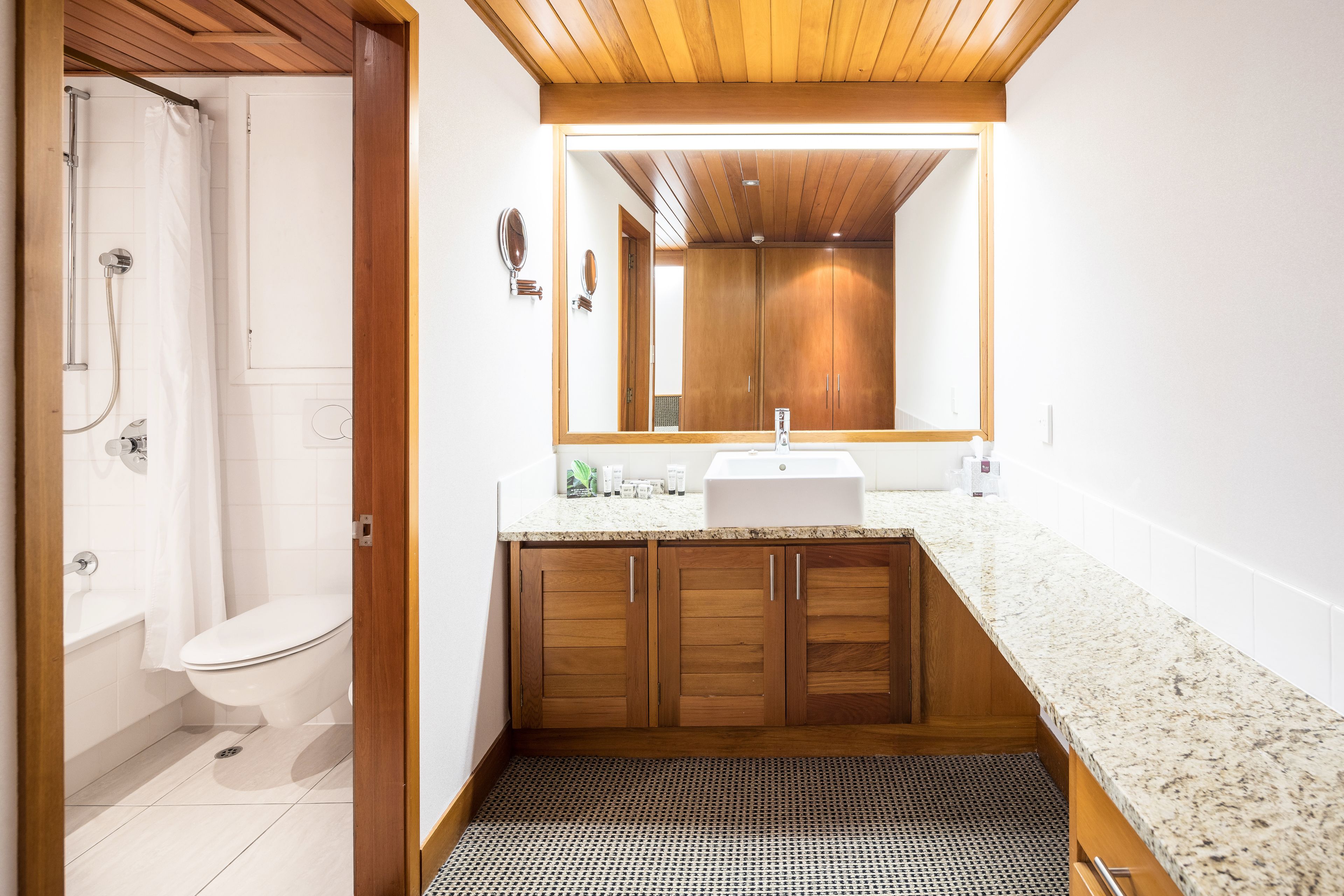 Une salle de bain moderne équipée d’une douche, de toilettes, d’un meuble-lavabo et d’armoires en bois.