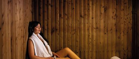 Una sauna de madera con un banco, una toalla y una botella de agua.
