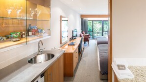 A modern kitchen with a stainless steel sink, a dining area with a table and chairs, and a view of the garden through large windows. - Commodore Airport Hotel (Christchurch)