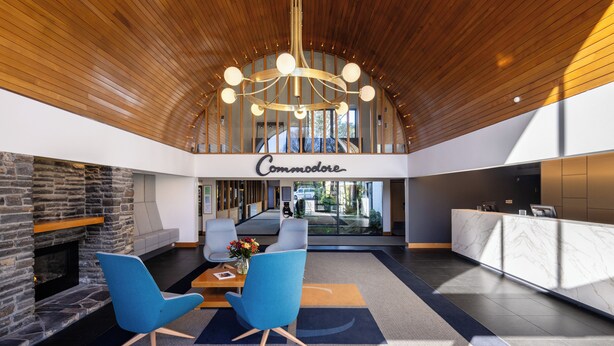 A spacious lobby with a stone fireplace, blue chairs, a marble reception desk, and a chandelier. - Commodore Airport Hotel (Christchurch)
