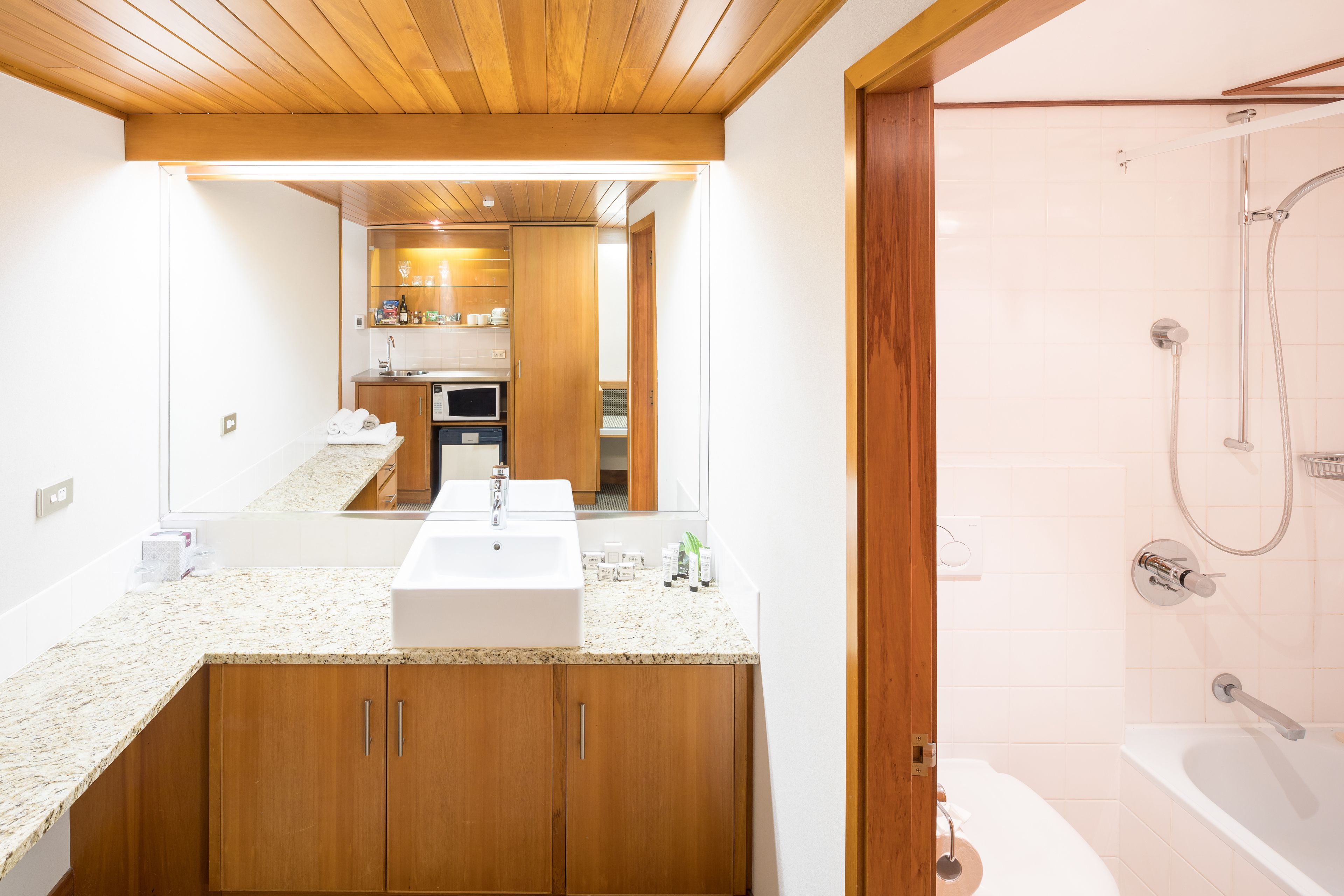 Un baño moderno con tocador de madera, un espejo grande y una zona de ducha separada.