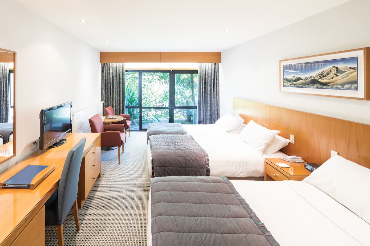 A hotel room with a bed, a desk with a computer, a chair, and a TV.