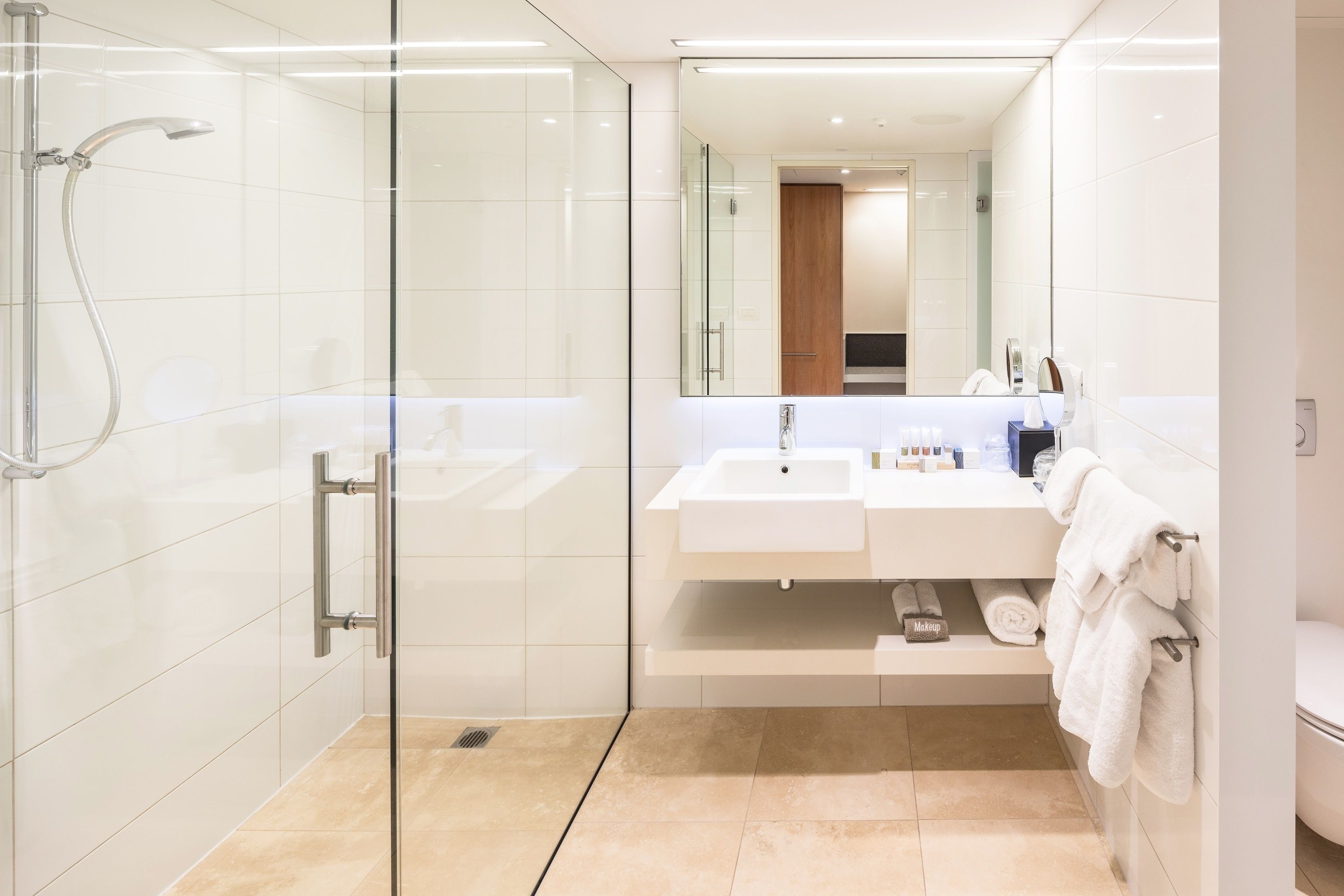 A modern bathroom with a glass-enclosed shower, a white sink, and a large mirror.