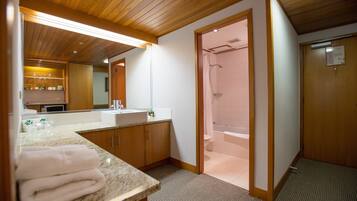 A modern bathroom with a wooden ceiling, a large mirror, a sink, and a shower area.