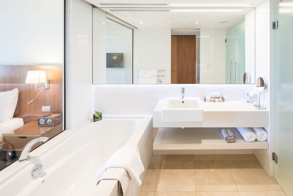 A modern bathroom with a large bathtub, a sink, and a mirror. - Commodore Airport Hotel (Christchurch)