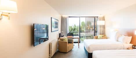 A hotel room with two beds, a TV, a desk, and a chair.