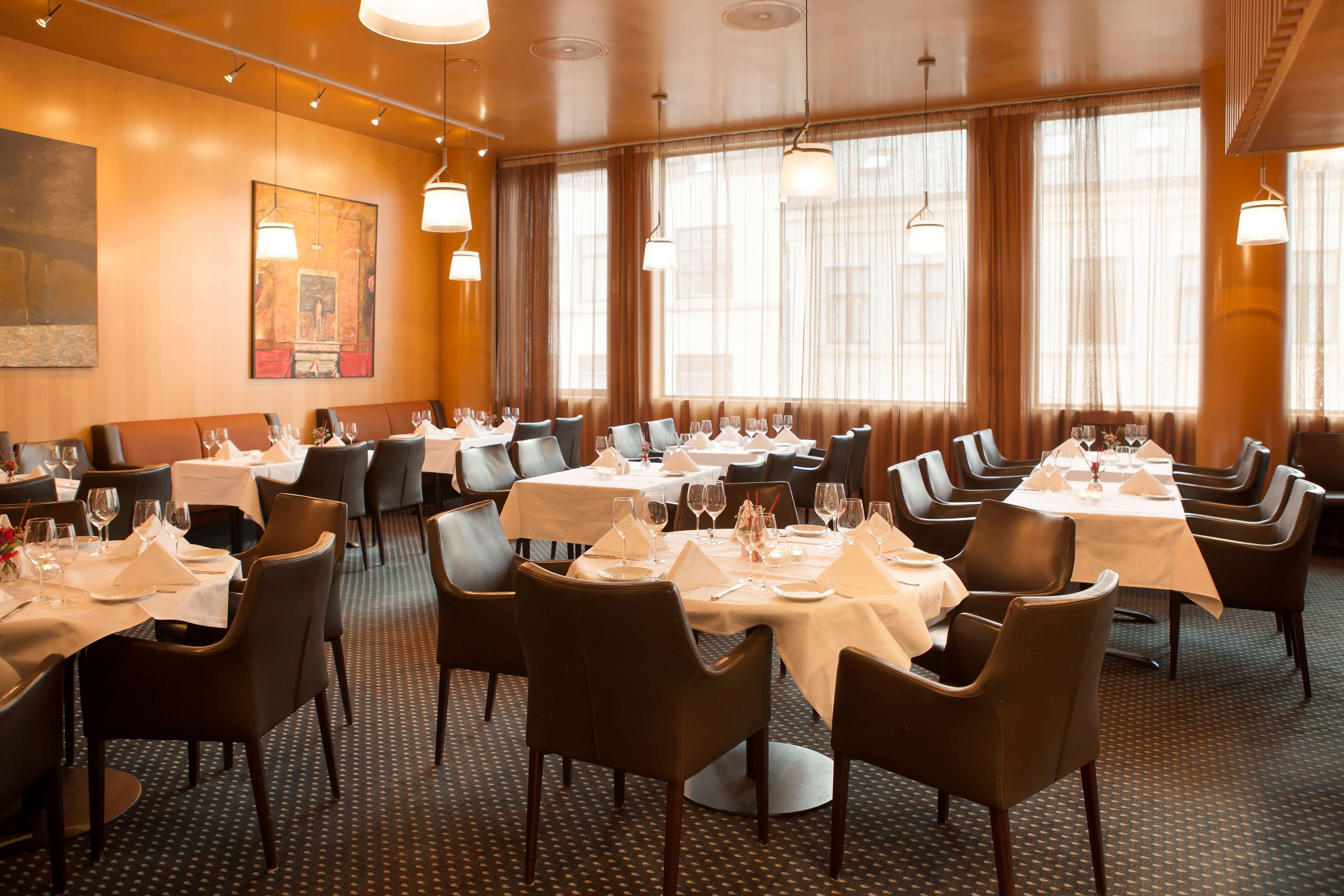 A restaurant with multiple tables set for dining, chairs, and a large window with curtains.