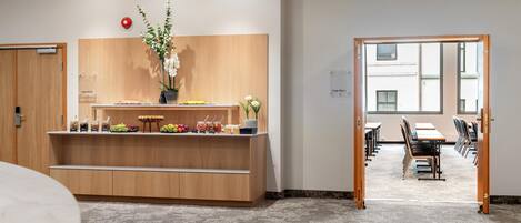 A reception area with a wooden counter, a vase of flowers, and a sign reading "Camp Room A".