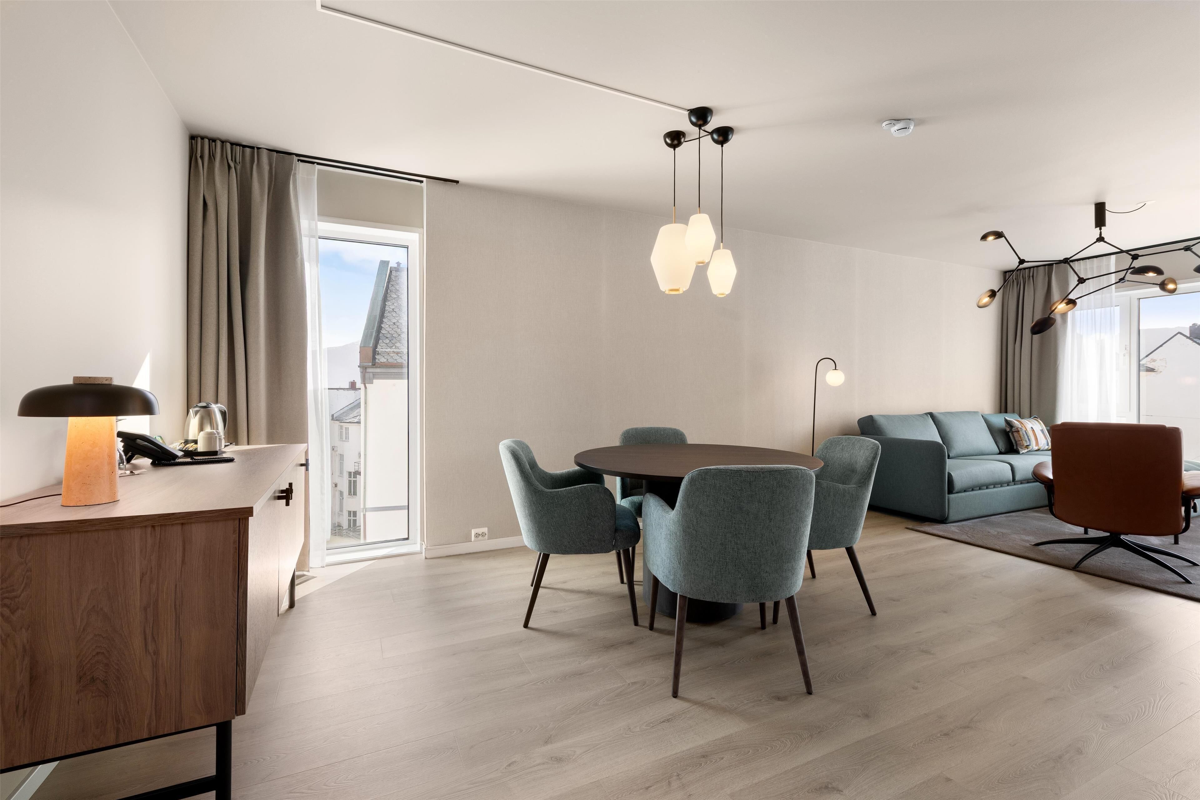Una sala de estar moderna con una mesa de comedor redonda, sillas tapizadas en gris, un sofá y una mesa de centro.