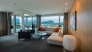 Une chambre d’hôtel moderne dotée d’une grande fenêtre donnant sur la ville, d’un canapé, d’une table basse et d’une chaise blanche.