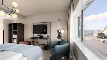 Una habitación de hotel moderna con cama, escritorio, silla, televisor y un amplio ventanal con vistas al mar.