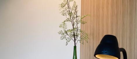 A wooden desk with a green vase, a black desk lamp, and a telephone.
