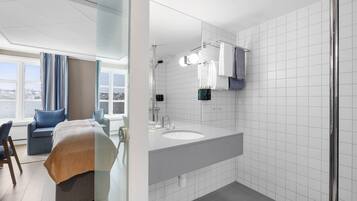 Un baño moderno con un espejo grande, azulejos blancos y una zona de ducha.